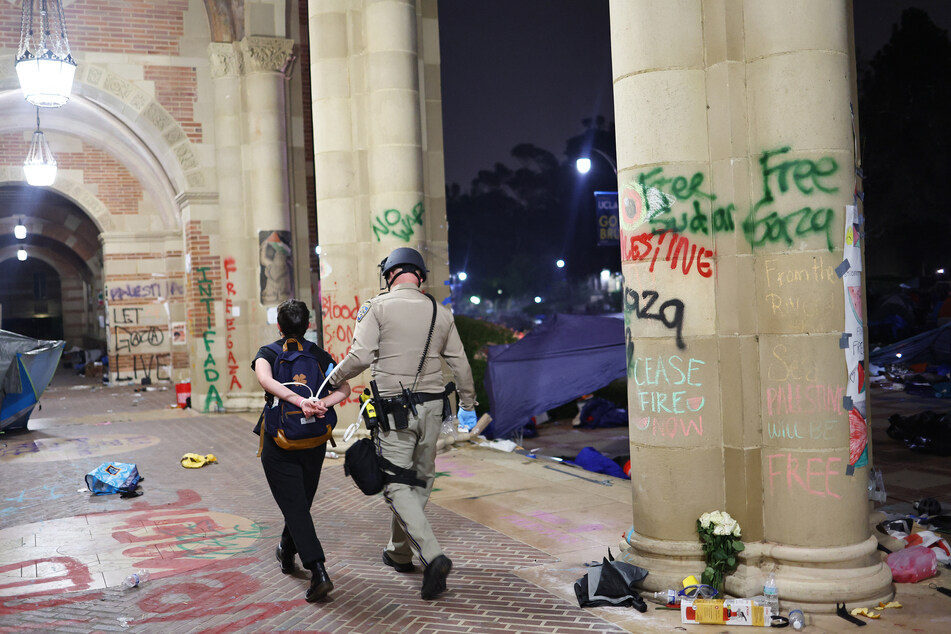 A California Highway Patrol (CHP) officer detains a protestor near encampment graffiti while clearing a pro-Palestinian encampment after dispersal orders were given at the University of California, Los Angeles (UCLA) campus on Thursday.