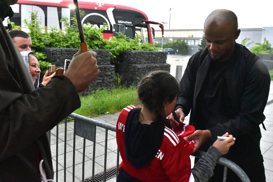 Vor dem Abflug zurück nach München nahmen sich einzelne Bayern-Akteure – hier: Trainer Vincent Kompany (39, r.) – im Regen noch kurz Zeit für die mitgereisten Fans.