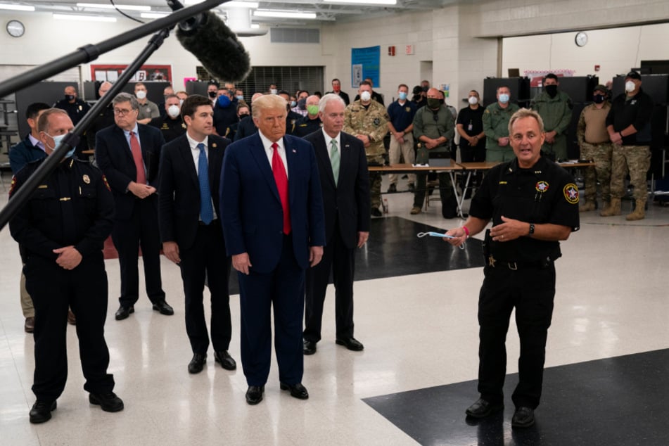 Donald Trump listens as Kenosha Sheriff David Beth (r) speaks at the Mary D. Bradford High School Emergency Room.