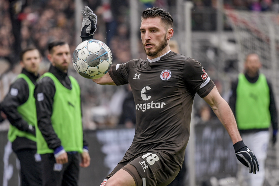 St. Paulis Dimitrios Diamantakos versucht einen Ball vor den Osnabrücker Auswechselspielern zu kontrollieren.