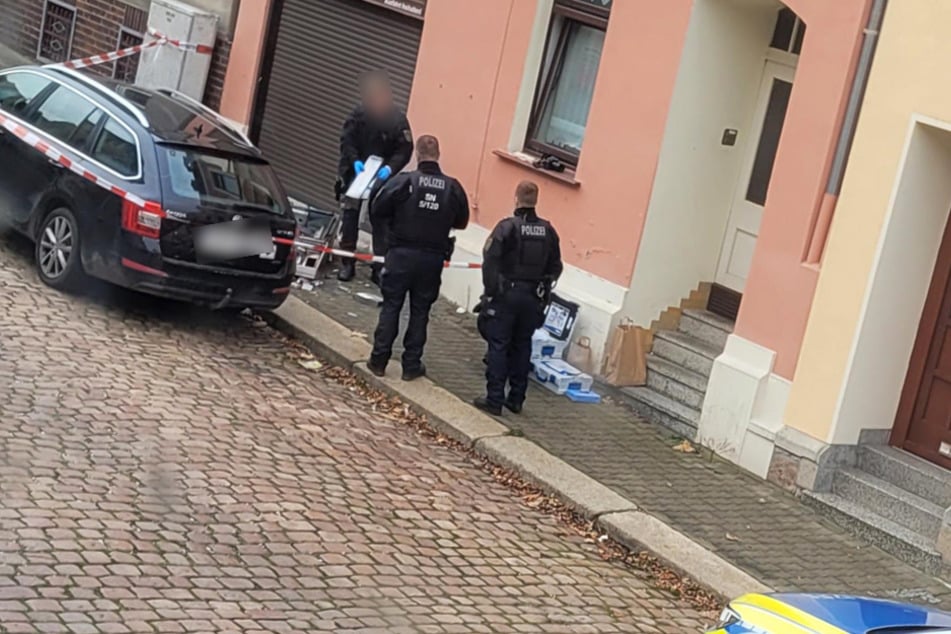 Polizisten kümmern sich um den gesprengten Automaten und den beschädigten Škoda.