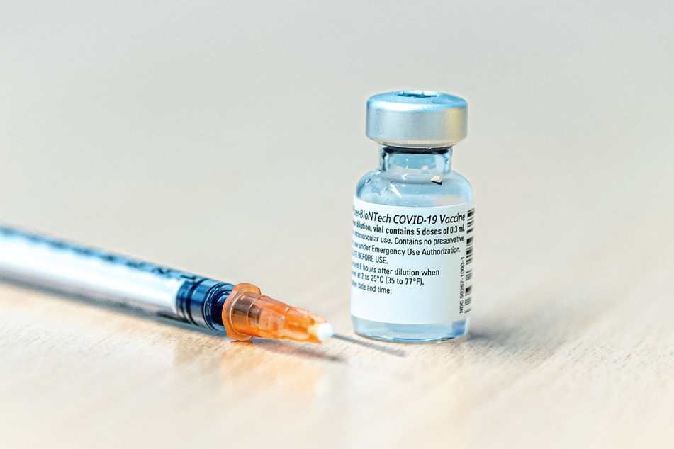 Eine Dosis mit dem Covid-19-Pfizer-Biontech-Impfstoff steht neben einer Spritze auf einem Tisch im Impfzentrum.