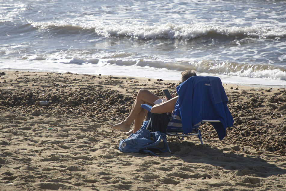 Ein Mann sonnt sich am Strand an einem sonnigen Tag mitten im Dezember.