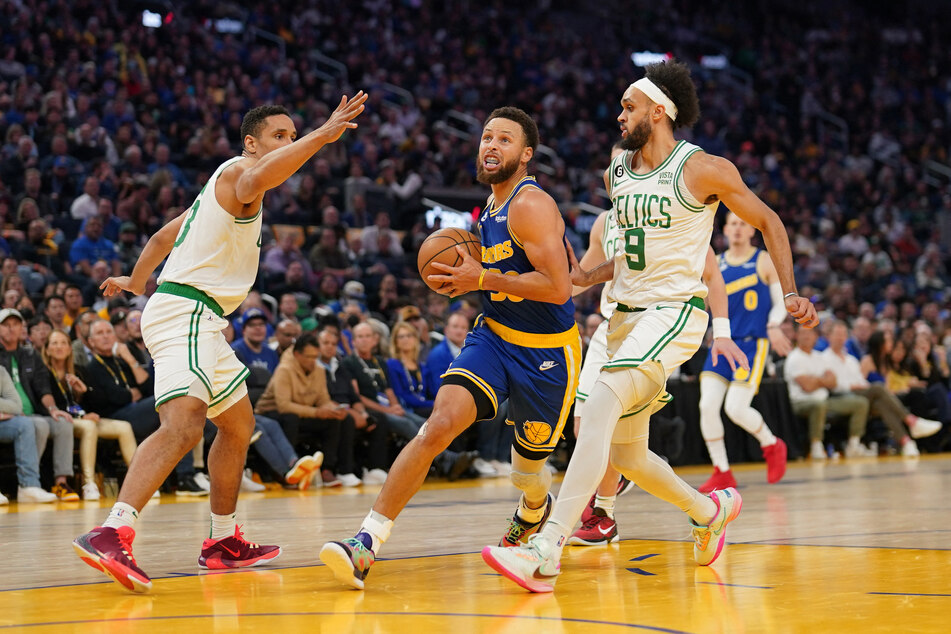 Golden State Warriors guard Stephen Curry drives to the basket against Boston Celtics guard Malcolm Brogdon and guard Derrick White in the third quarter at the Chase Center.