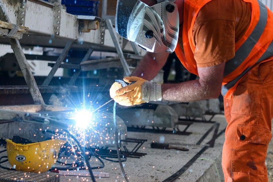 Ein Bauarbeiter schweißt auf einer Bahn-Baustelle. Die Wirtschaft hofft, dass der geplante Ausbau der Infrastruktur Beschäftigung in Deutschland sichert.