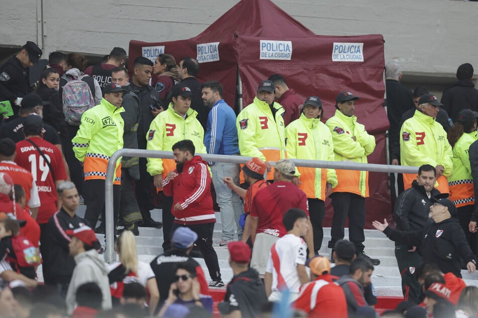 Polizisten und Sicherheitskräfte sichern einen Bereich, in dem ein Zuschauer im Monumental-Stadion von der Tribüne gestürzt ist.