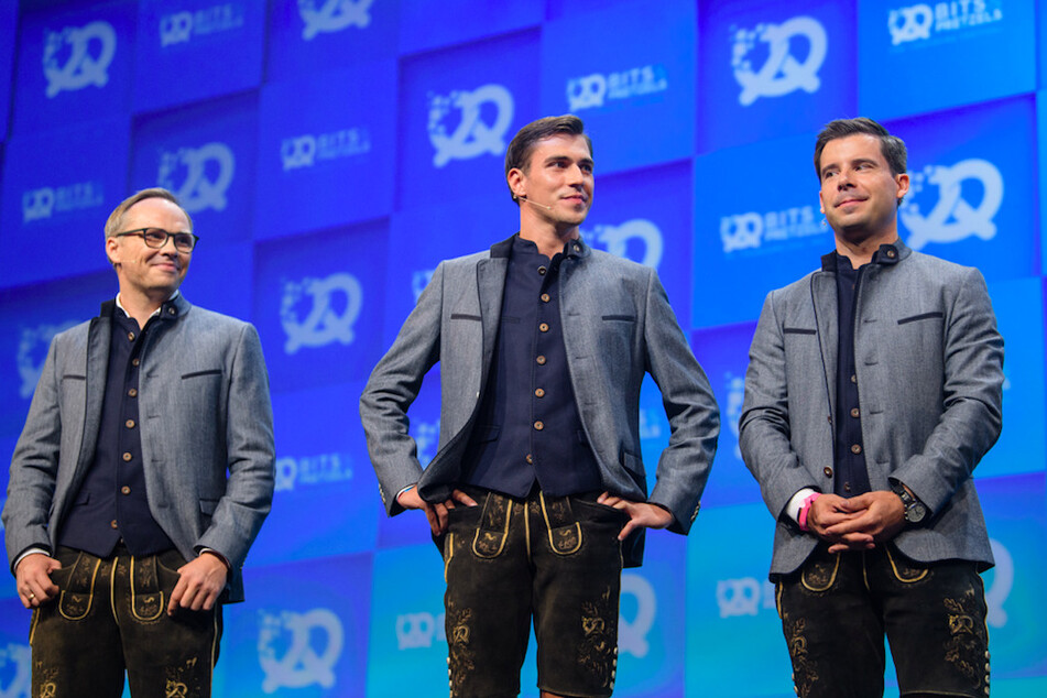 Bernd Storm van's Gravesande, Andreas Bruckschlögl und Felix Haas (v.l.n.r.), Gründer der Bits & Pretzels, stehen während der Eröffnung 2019 auf der Bühne. In diesem Jahr findet die Messe online statt.