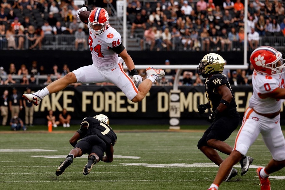 Davis Allen of the Clemson Tigers jumps over Gavin Holmes of the Wake Forest Demon Deacons during the first half of their game at Truist Field.