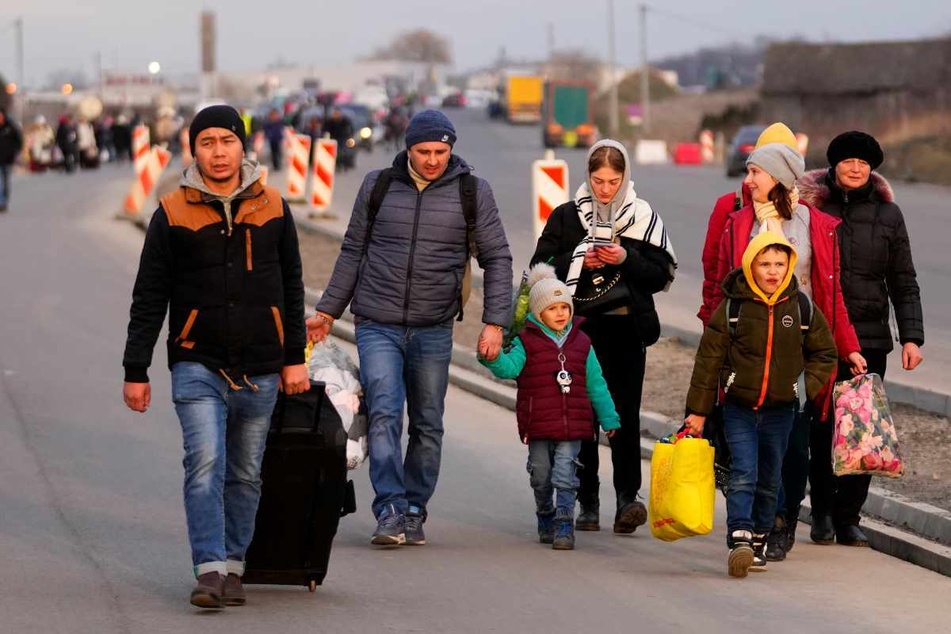 Przemysl (Polen): Ukrainische Flüchtlinge gehen mit ihrem Gepäck eine Straße entlang.