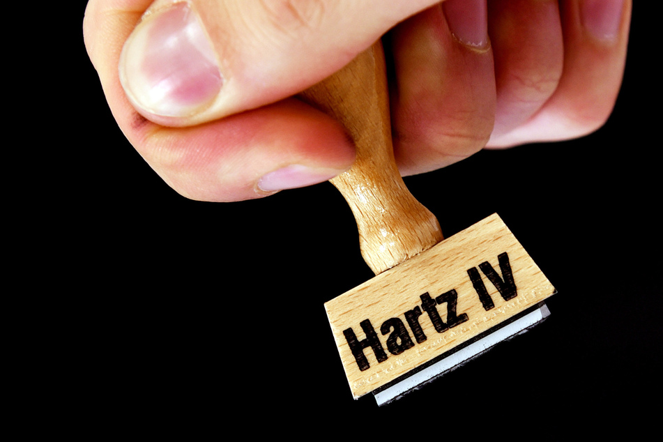 Eine Hand hält einen Stempel mit der Aufschrift "Hartz IV". (Symbolbild)