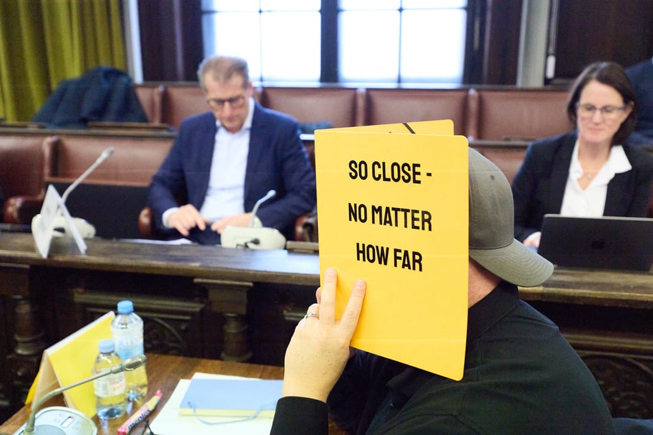 Der angeklagte Sicherheitsunternehmer mit einer Botschaft für die Pressefotografen. Im Hintergrund: Stephan Hensel (51, l), Vater der Block-Kinder und Ex-Mann der Unternehmerin.