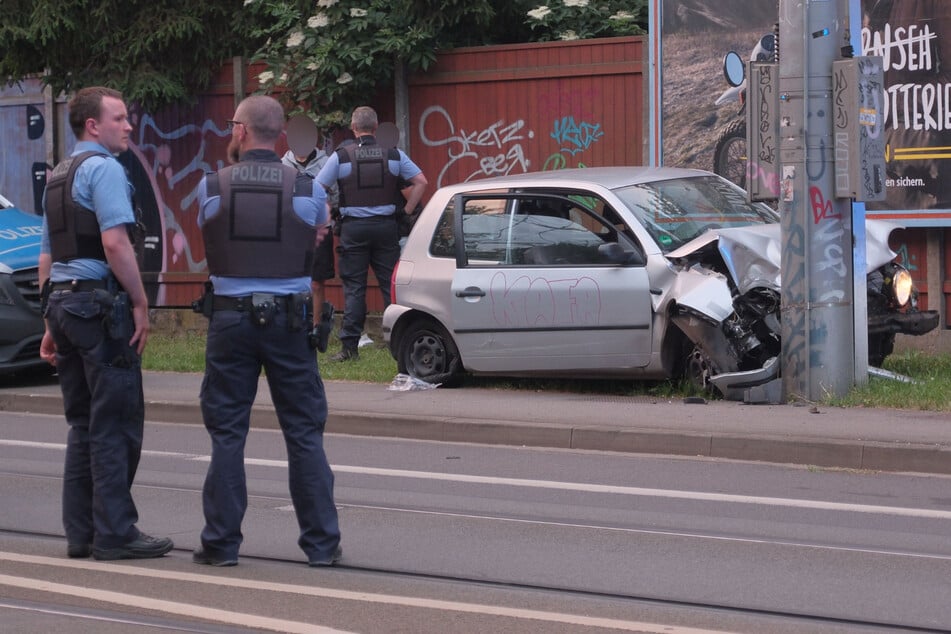 Ende einer Wahnsinnsfahrt: Mit zerschossenen Reifen klebt der VW Lupo mit dem "KAFA"-Tag an der Tür am Mast. Im Hintergrund bewacht ein Polizist zwei Insassen.