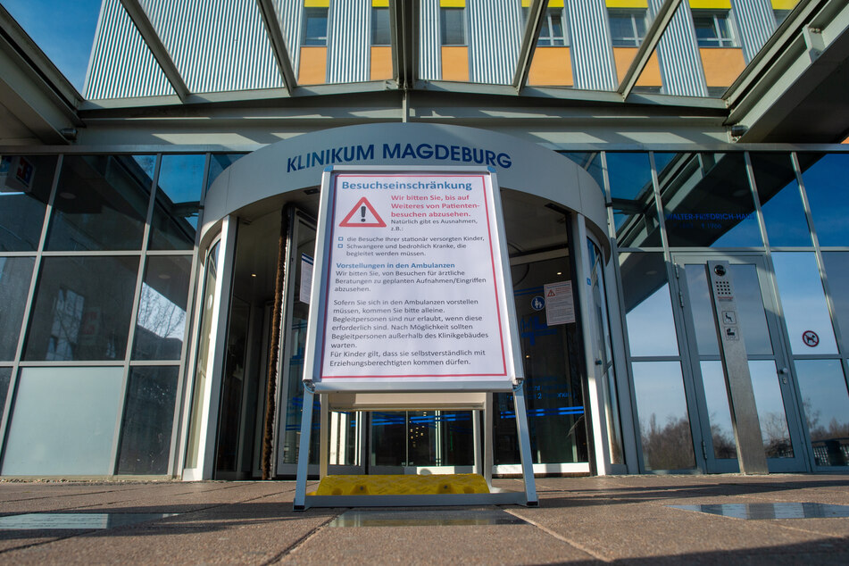 Ein Schild steht vor dem Haupteingang des Klinikums Magdeburg auf dem die Überschrift "Besuchseinschränkung" zu lesen ist. Das Klinikum bittet bis auf weiteres von Patientenbesuchen abzusehen. 