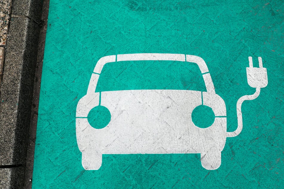 Ein stilisiertes Auto auf grünem Grund markiert einen Parkplatz mit Ladesäule für Elektrofahrzeuge. (Symbolbild)
