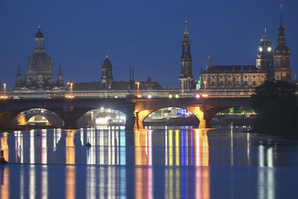 Die Lichter der Straßenbeleuchtung spiegeln sich am Morgen in der Elbe vor der Altstadt von Dresden.