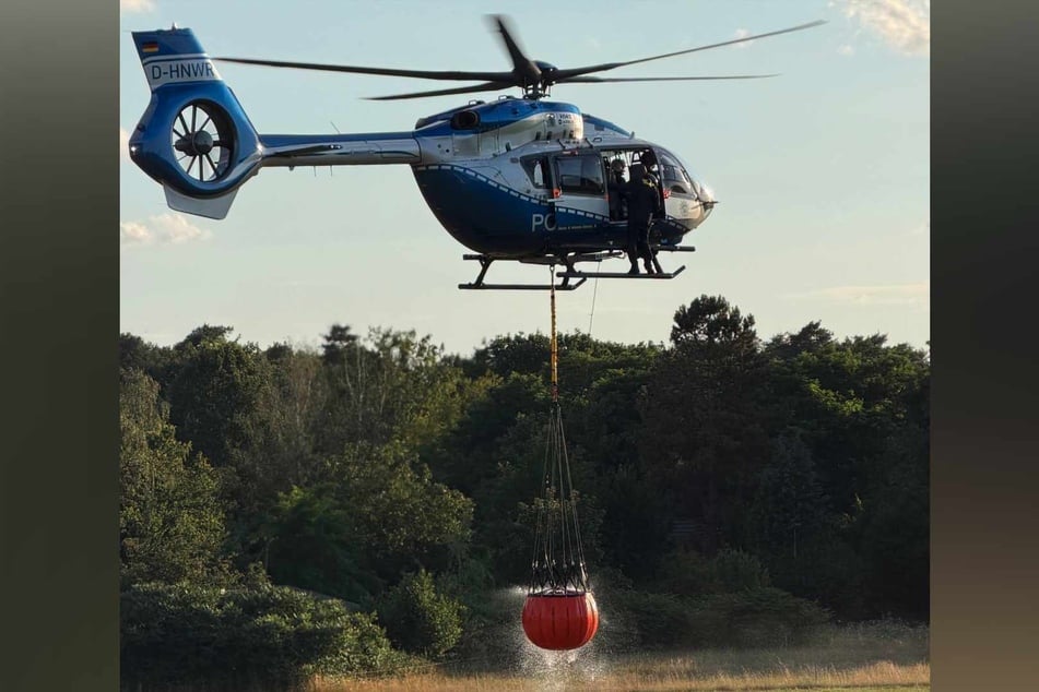 Zur Unterstützung aus der Luft kreiste am Montag ein Polizeihubschrauber mit Wasserbehälter über die Wahner Heide.