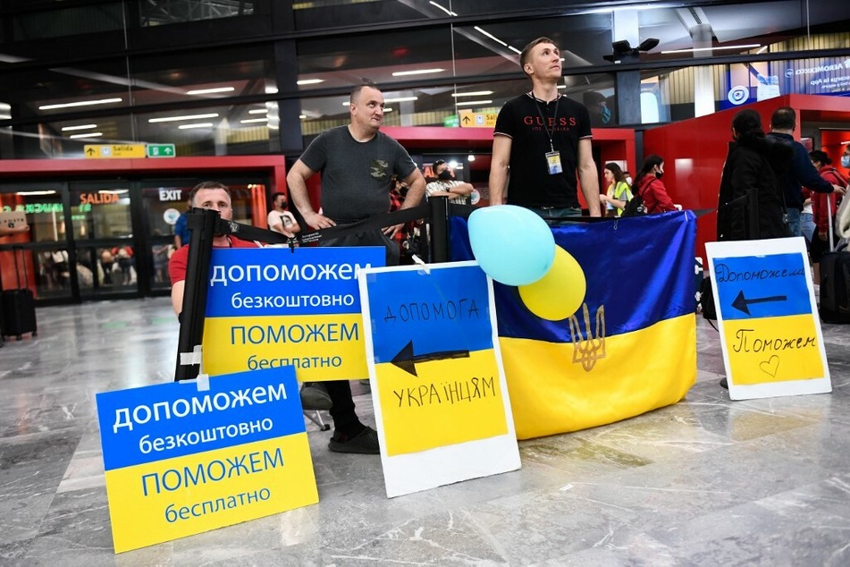 Volunteers with signs welcome Ukrainian refugees as they arrive at the Tijuana airport to help them on their journey to the United States.
