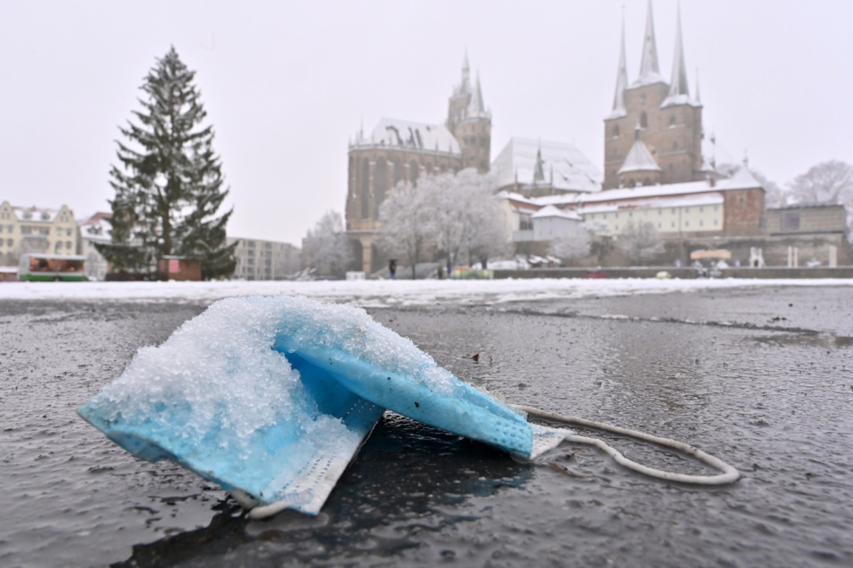 Eine gebrauchte Maske liegt im Schnee: In Thüringen sind die Corona-Fallzahlen weiter auf hohem Niveau. (Symbolbild)