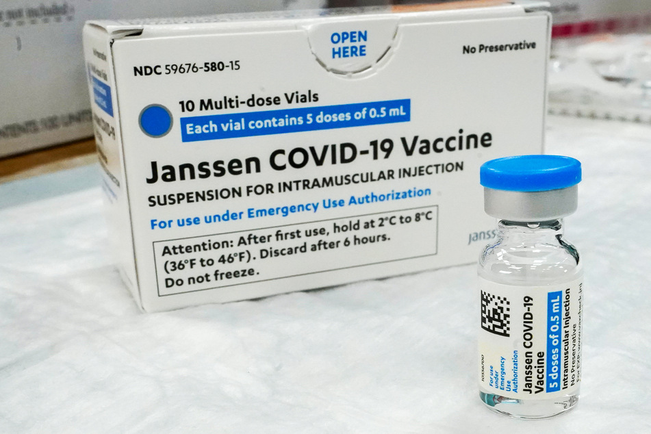 Eine Packung des "Johnson & Johnson"-Impfstoffs steht hinter einer solchen Ampulle bereit zum Impfen.