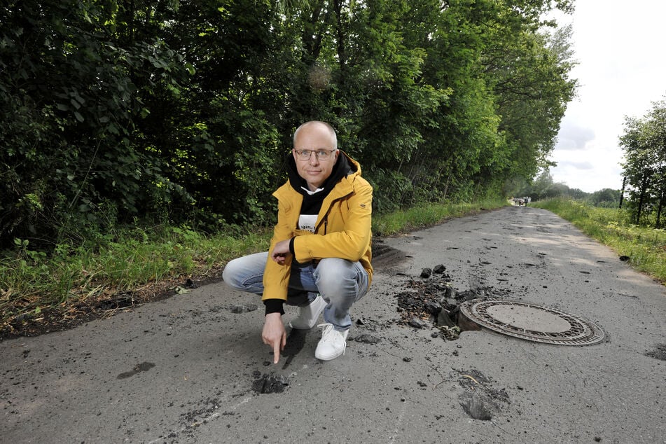 Ivo Partschefeld (47) zeigt auf die Löcher im Asphalt.