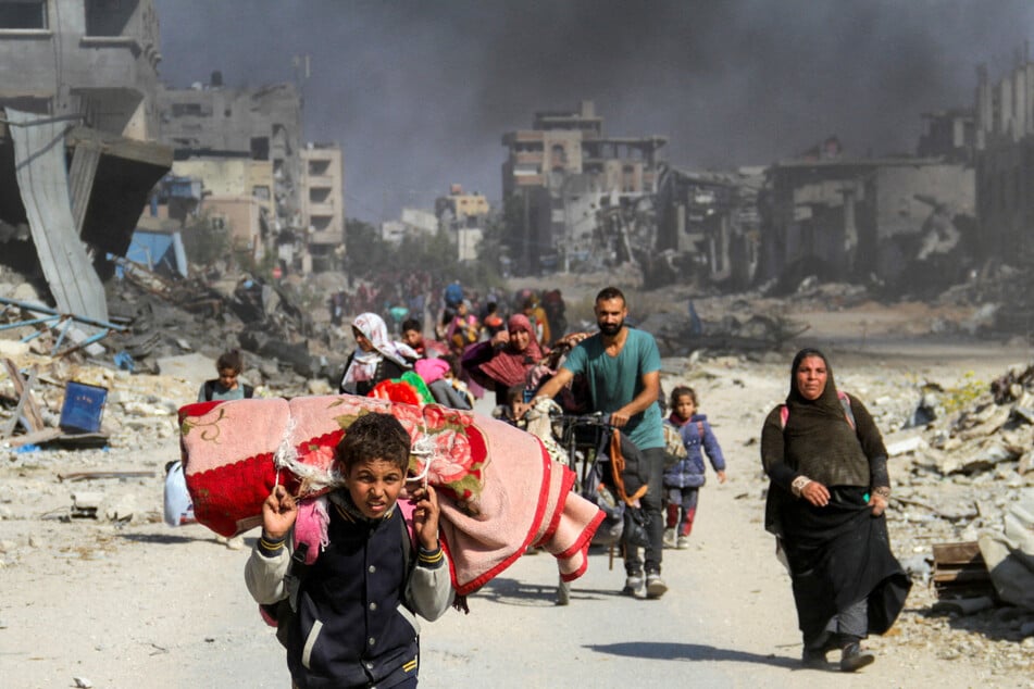 Forcibly displaced Palestinians carry their belongings in Gaza City after fleeing the northern part of Gaza amid the Israeli assault.