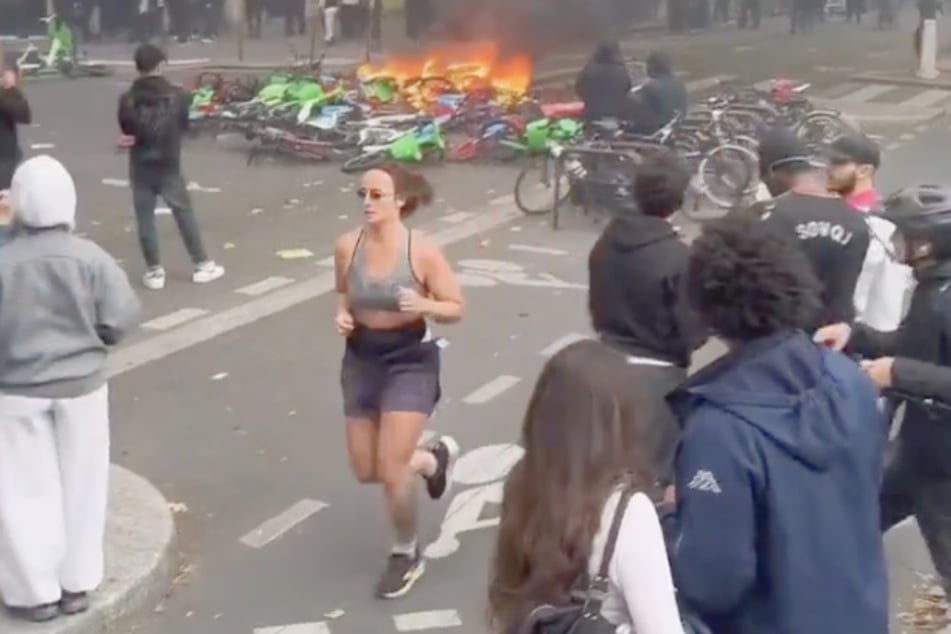 Diese Joggerin dreht unbeeindruckt ihre Runden durch die Randale von Paris. Trainingspläne müssen eben eingehalten werden ...