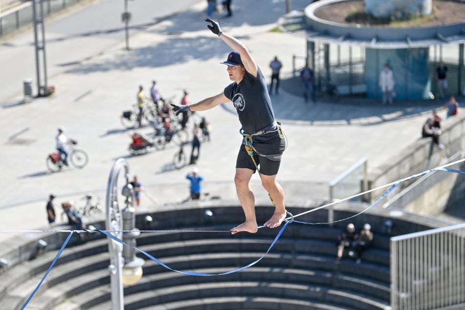 Peter Bessler balanciert über dem Theaterplatz in Chemnitz in rund 20 Metern Höhe über eine Slackline bei einer Werbeaktion für das Slackfest.