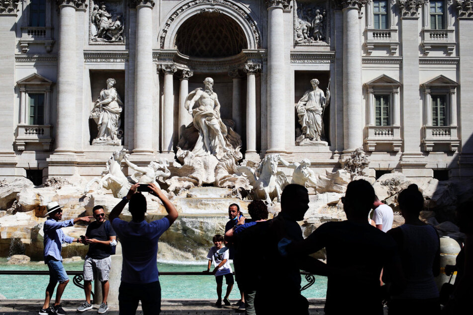 Touristen fotografieren den Trevi-Brunnen in Rom. Aufgrund der seit Tagen anhaltenden heißen Temperaturen halten sich nur wenige Touristen in der historischen Stadtmitte auf.