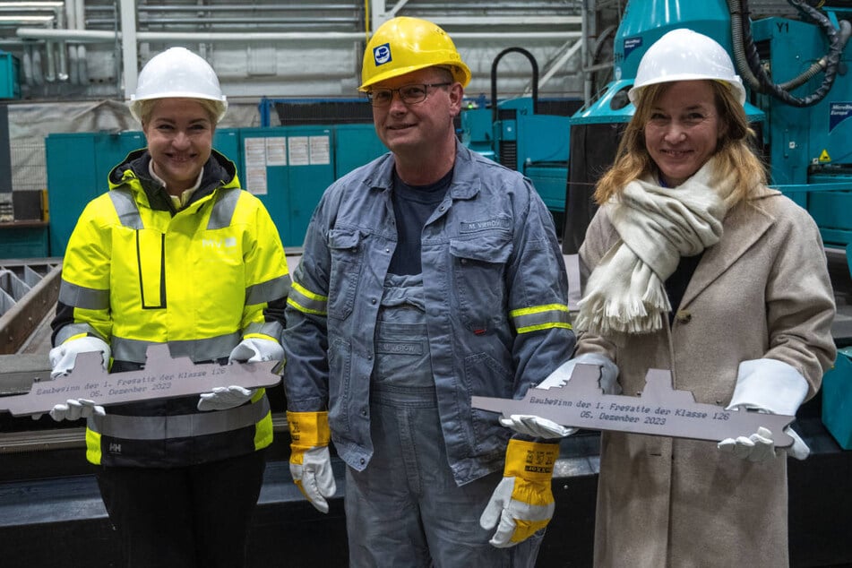 Mecklenburg-Vorpommerns Ministerpräsidentin Manuela Schwesig (49, SPD, v.l.n.r.), Werftarbeiter Marko Vierow und Staatssekretärin Siemtje Möller (40, SPD) stehen zum offiziellen Baubeginn der F126 in einer Werfthalle.