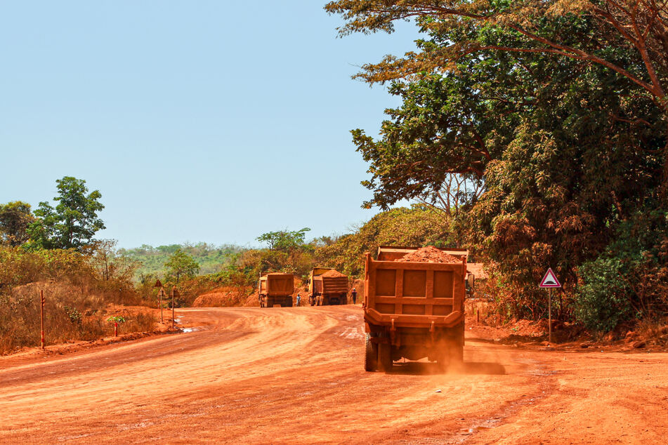 Lastwagen transportieren Bauxit entlang einer Bergbau-Transportstraße.