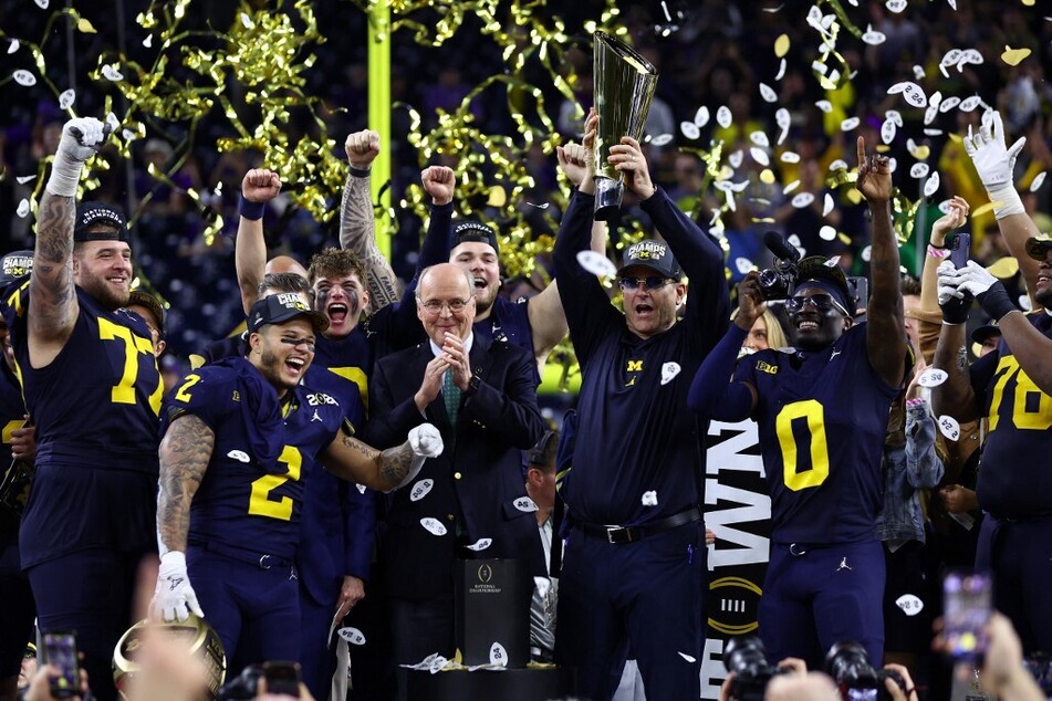 Head coach Jim Harbaugh of the Michigan Wolverines and his team react as he lifts the national championship trophy after defeating the Washington Huskies during the 2024 CFP National Championship game at NRG Stadium in Houston, Texas.