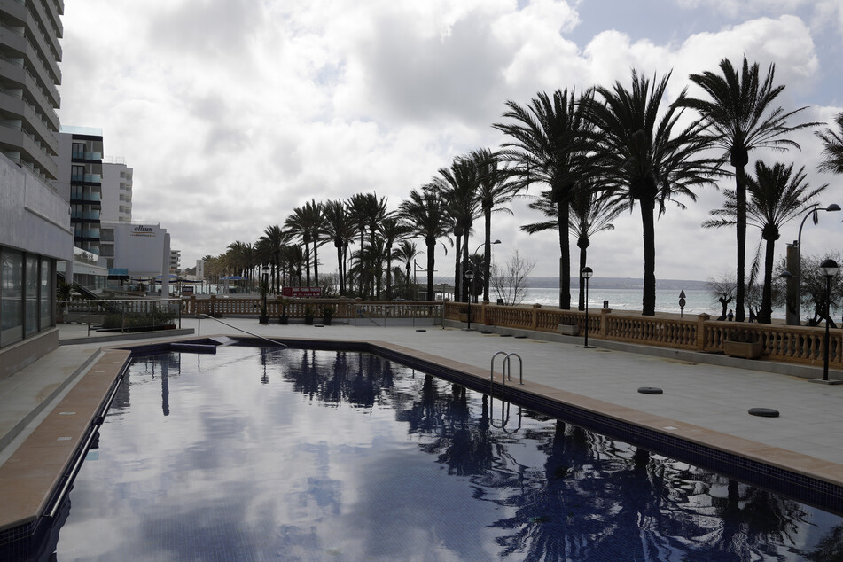 Palmen spiegeln sich im Pool eines geschlossenen Hotels am Strand von Arenal. Mallorca gilt ab Sonntag nicht mehr als Risikogebie.