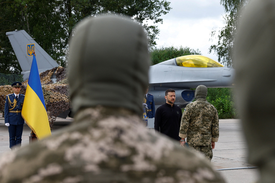 Ukraine's President Volodymyr Zelenskiy awards a military pilot next to an F-16 fighting jet on the Day of the Ukrainian Air Forces.