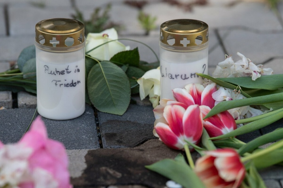 Kerzen und Blumen erinnern nach dem gewaltsamen Tod zweier Kinder auf dem Innenhof eines Hochhauses in Hanau an die Opfer.