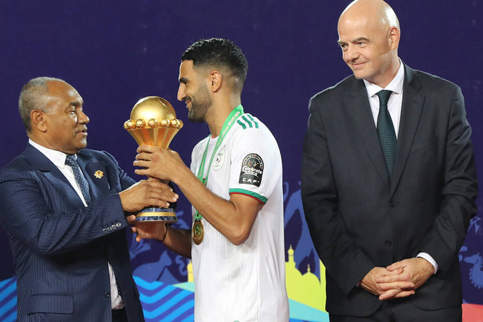 Riyad Mahrez erhält von CAF-Präsidenten Ahmad Ahmad die Afrika-Cup-Trophäe. Nach einem Freistoßtreffers in der fünften Minute der Nachspielzeit gewann Algerien mit 2:1 gegen Senegal.