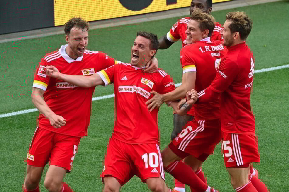 Die Union-Kicker feiern gemeinsam mit Torschütze Max Kruse (2.v.l.) den späten 2:1-Siegtreffer gegen RB Leipzig am letzten Spieltag der vergangenen Bundesliga-Saison, der ihnen die Qualifikation für die UEFA Conference League ermöglicht hat.