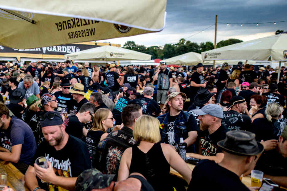 Wacken-Besucher sitzen beim Auftritt der Feuerwehrkapelle an Biertischen. Wenig später musste der Platz geräumt werden.