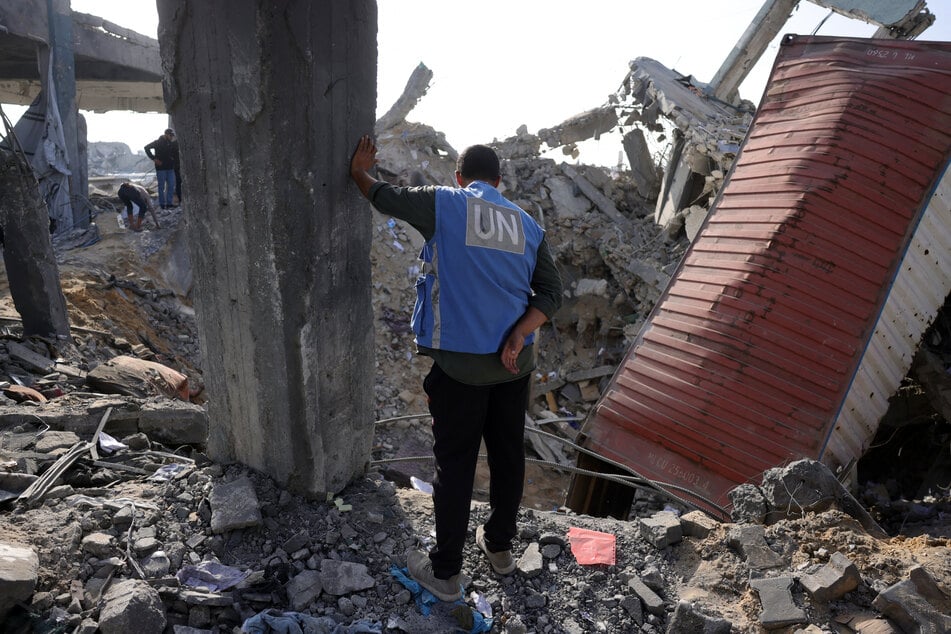 A UN worker stands amid the rubble of an UNRWA aid supply depot and shelter, heavily damaged in an overnight Israeli strike in Jabalia in the northern Gaza Strip on May 10, 2025.