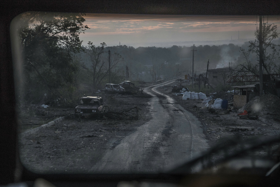 Während schwerer Kämpfe an der Front in Sjewjerodonezk in der Region Luhansk liegen ausgebrannte Autowracks am Rand eines Wegs.