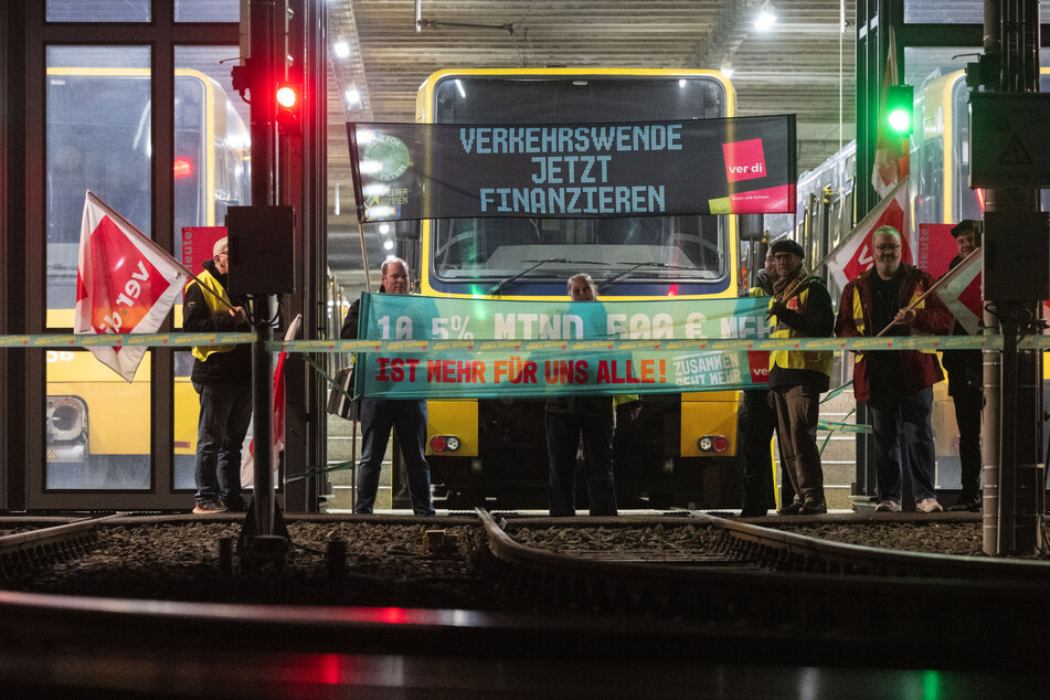 Teilnehmer eines Warnstreiks stehen vor einem Stadtbahndepot der Stuttgarter Straßenbahnen AG (SSB).