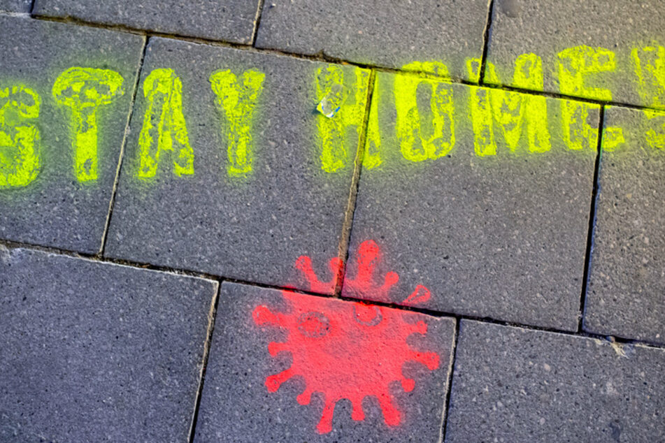 Ein Graffiti bestehend aus dem Text "Stay Home" und einer symbolischen Virusdarstellung ist in der Münchner Fußgängerzone auf den Boden gesprüht worden.