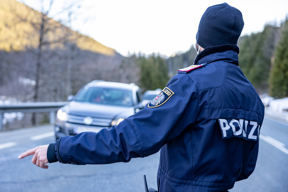 Ein Polizist kontrolliert Fahrzeuge auf der Pass-Thurn-Straße in Kitzbühel, Österreich kurz vor der Landesgrenze zu Salzburg.