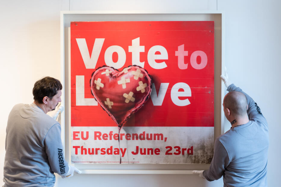 Mitarbeiter richten bei einer Pressevorbesichtigung im Münchner Büro vom Auktionshaus Sotheby's das Werk "Vote to love" von Banksy aus.