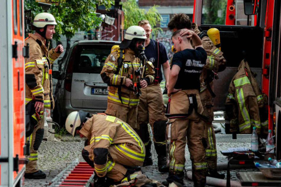 Feuerwehrmänner stehen nach dem Einsatz an der Straße Am Flutgraben in Kreuzberg.