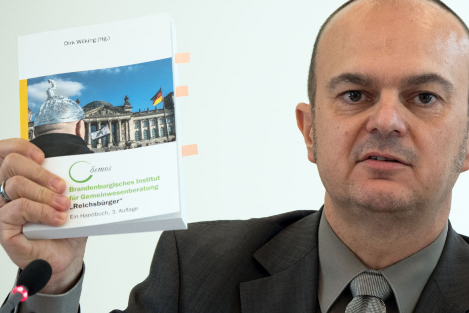 Der Leiter des Brandenburger Verfassungsschutzes, Frank Nürnberger, zeigt während einer Pressekonferenz ein Handbuch zum Umgang mit den sogenannten Reichsbürgern.