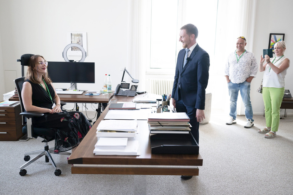 Rollentausch: Besucherin Emily Schön hat hinter dem Schreibtisch von MP Michael Kretschmer Platz genommen.