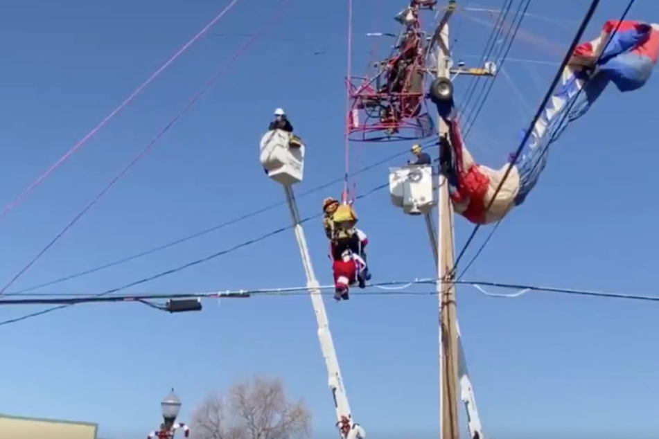 A firefighter helps Santa down from his sleigh, which is tangled in the power lines.