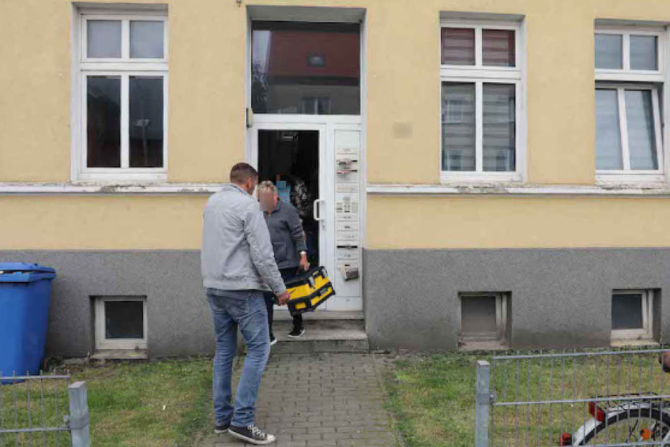 Kriminalbeamte verlassen nach der Spurensicherung durch die eingetretene Tür den Tatort.