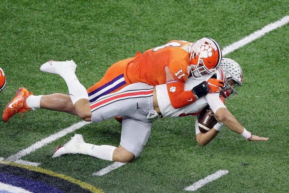 Justin Fields (r) of The Ohio State Buckeyes is tackled by Bryan Bresee of the Clemson Tigers in the first half against the Clemson Tigers during the College Football Playoff semifinal game.