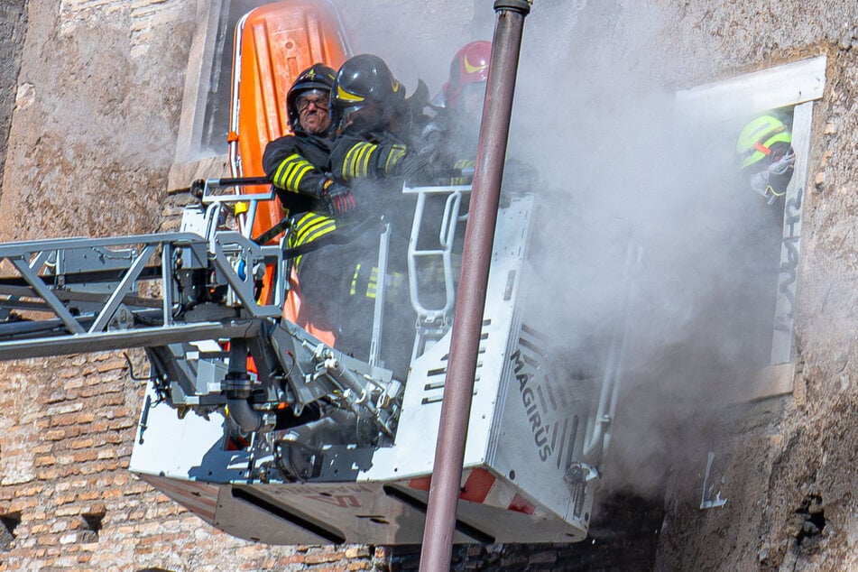 Einsatzkräfte der Feuerwehr gehen nach dem zweiten Einsturz eines Gebäudeteils in Deckung.